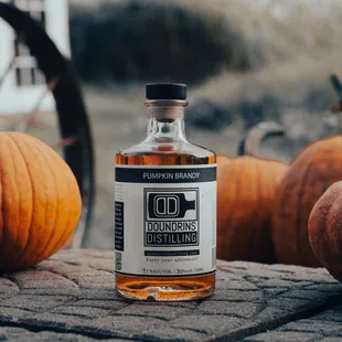 a bottle of liquor sitting in front of pumpkins