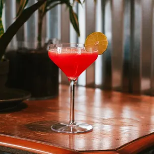 a red drink with a slice of lemon