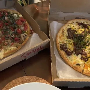 two pizzas in boxes on a table