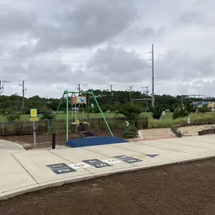 Hopscotch in the foreground and an adaptive swing in the background.