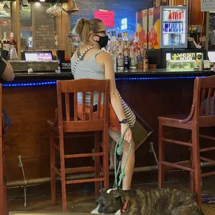 a woman sitting at a bar with her dog