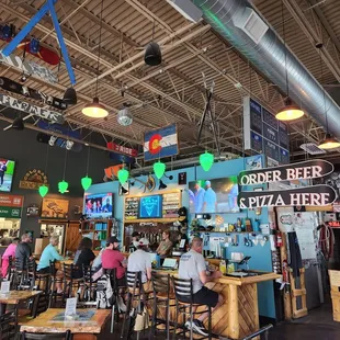 A busy bar with taps and t.v.&apos;s. To the left is a woodburning pizza kitchen. So yummy