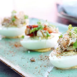 Crab Deviled Eggs: three deviled eggs topped with old bay, dungeness crab ($7).