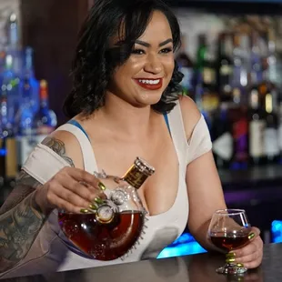 a woman pouring a drink at a bar