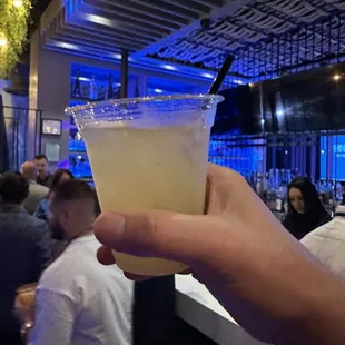 a person holding a drink at a bar