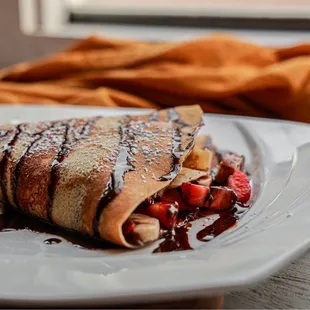 a crepe with whipped cream and chocolate sauce