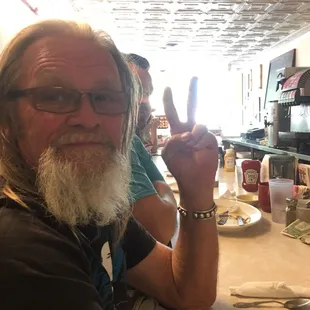 a man sitting at a table with a peace sign