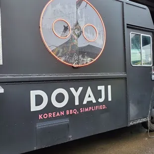 a black food truck with a neon sign