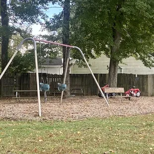 Two toddler swings to the side of the park