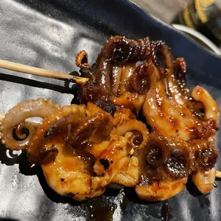 octopus skewered on a black plate with chopsticks