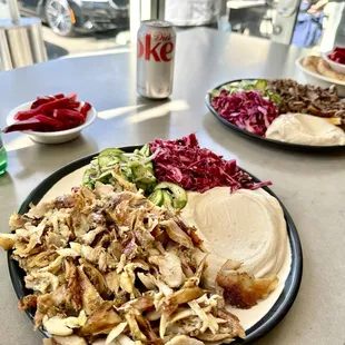 Chicken Shwarma plate with 4 sides  (front), beef shwarma plate (right) and couple of pita breads