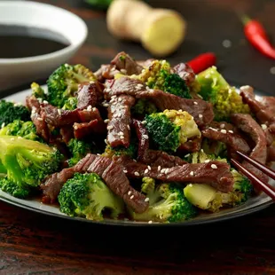 a beef and broccoli dish with chopsticks