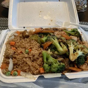 a takeout container with rice, broccoli, and carrots