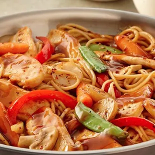 a pan of noodles with chicken and vegetables