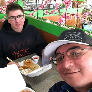 two men sitting at a table with food