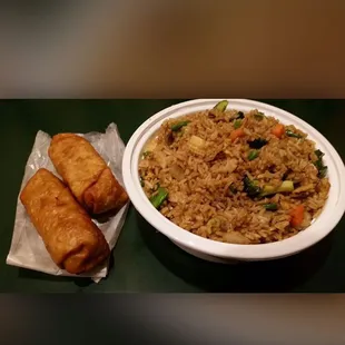 a plate of fried rice and egg rolls
