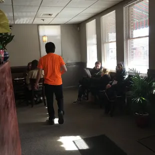 a man in an orange shirt walking through a waiting room
