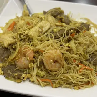 a plate of noodles with shrimp and vegetables