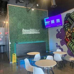 tables and chairs in front of a mural