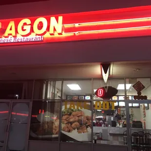 the front of a restaurant with a neon sign