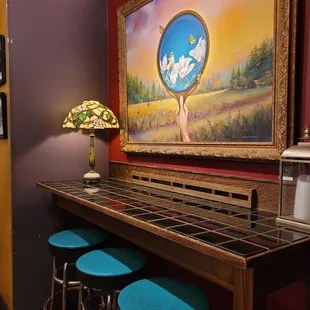 a bar with stools and a painting on the wall