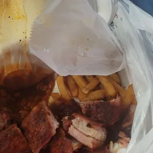 a plastic bag full of meat and fries