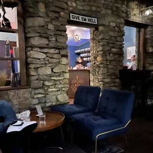 a living room with blue chairs and a stone wall
