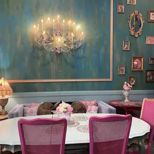 a table with pink chairs and a chandelier