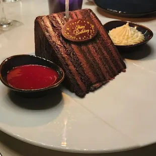 a piece of chocolate cake with a lit candle