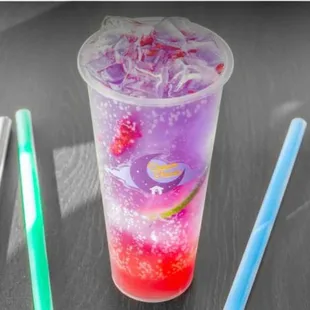 a purple drink with a straw and two strawberries