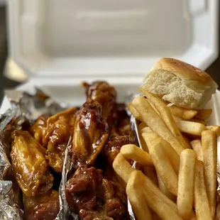 chicken wings and french fries in a styrofoam container