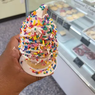 a hand holding an ice cream cone with sprinkles
