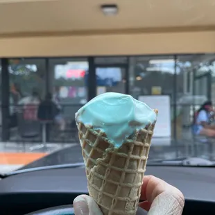 a hand holding a cone of ice cream