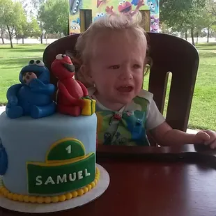 a toddler sitting in a high chair with a birthday cake in front of him