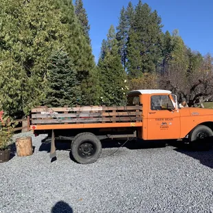 n orange truck parked in a gravel lot