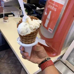Pralines and cream single scoop in a waffle cone.