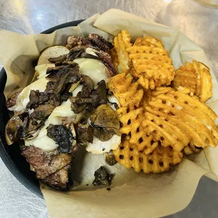 ribeye sandwich topped with mushrooms and swiss cheese