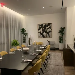 a long dining table with yellow chairs