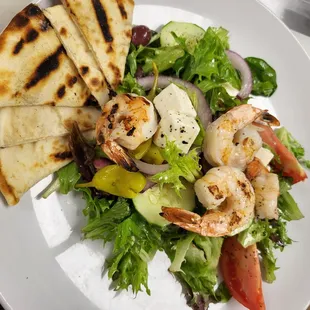 a plate of salad with grilled shrimp