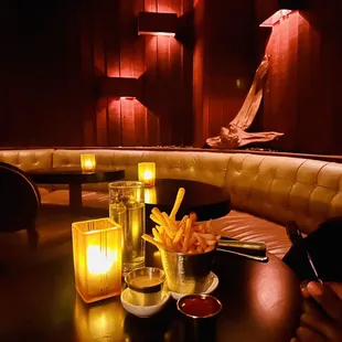 a corner booth with candles and a table with french fries
