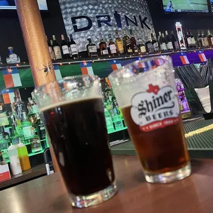 two beers sitting on a bar