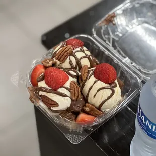 a plastic container of ice cream and strawberries