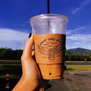 a hand holding a cup of iced coffee