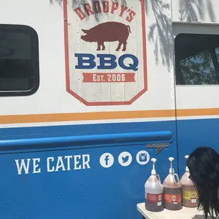 a woman sitting at a table in front of a bbq truck