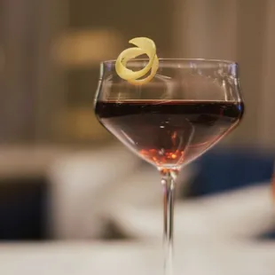 a glass of wine with a lemon garnish