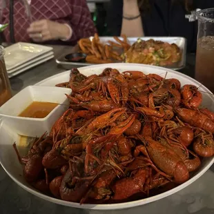 a plate of craws and a bowl of sauce