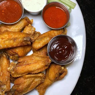 a plate of chicken wings with dipping sauces