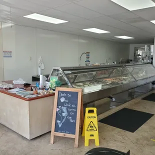 Refrigerated display containing poke, ceviche, shellfish, whole fish, and fillets.