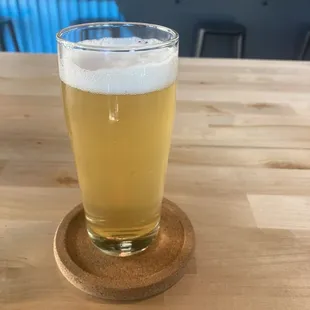 a glass of beer on a wooden coaster