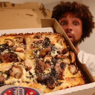 a man holding a box of pizza